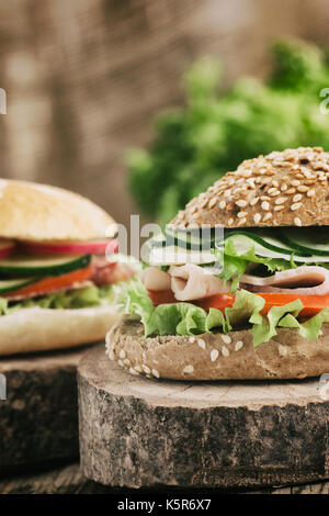Leckeren Schinken, Käse und Salami Sandwich mit Gemüse, Salat, Kirschtomaten in natürlichen Umgebung mit hölzernen Hintergrund Stockfoto