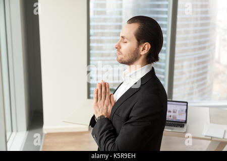 Erfolgreicher Geschäftsmann meditieren am Arbeitsplatz in modernen Büro. Stockfoto