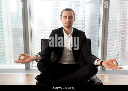 Erfolgreicher Geschäftsmann meditieren am Arbeitsplatz in modernen Büro. Stockfoto