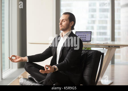 Erfolgreicher Geschäftsmann meditieren am Arbeitsplatz in modernen Büro. Stockfoto