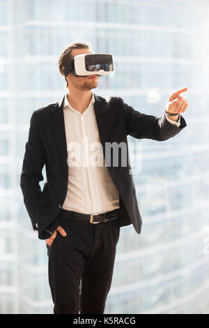 Unternehmer im VR-Brille zeigenden Finger in der Luft. Stockfoto