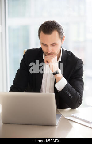 Ernste nachdenkliche Geschäftsmann Arbeiten am Laptop im Büro. Stockfoto