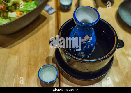 Japanische Hot Sake in heißem Wasser Schüssel auf hölzernen Tisch Hintergrund Stockfoto