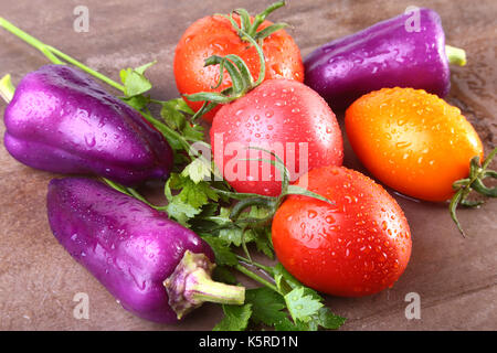 Verschiedene Gemüse mit lila exotischen Farbe Paprika und Tomaten auf Stein Hintergrund isoliert. Stockfoto