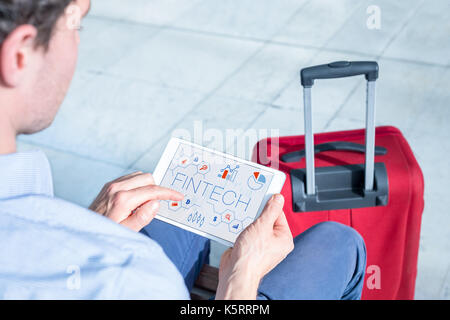 Geschäftsmann am Flughafen mit digitalen Tablet Computer mit infografik Konzept der fintech (Financial Technology) auf dem Bildschirm, Business Travel Stockfoto