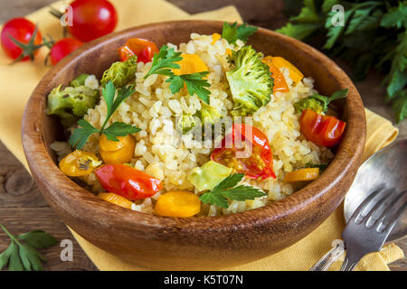 Mit Gemüse: Tomaten, Karotten, Zucchini, Brokkoli und Petersilie im rustikalen Houten - Gesunde vegetarische Kost Bulgur Stockfoto
