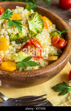 Mit Gemüse: Tomaten, Karotten, Zucchini, Brokkoli und Petersilie im rustikalen Houten - Gesunde vegetarische Kost Bulgur Stockfoto