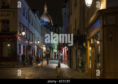 Touristen zu Fuß in einem kleinen malerischen Straße in Montmartre in Paris am Heiligen Abend mit schönen Lichter. Stockfoto