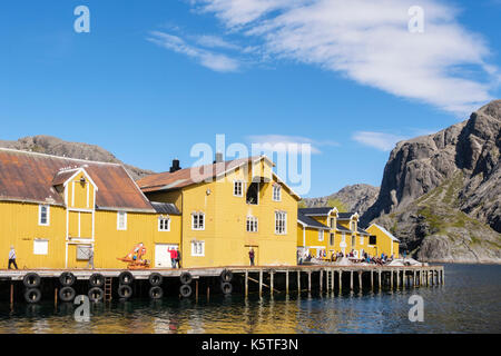 Alte gelbe Holzhäusern auf Stelzen im historischen Fischerdorf Hafen. Nusfjord, Insel Flakstadøya, Lofoten, Nordland, Norwegen Stockfoto