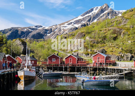 Boote Rorbu und Touristen in den Hafen von historischen Fischerdorf in atemberaubender Landschaft. Nusfjord, Insel Flakstadøya, Lofoten, Nordland, Norwegen Stockfoto