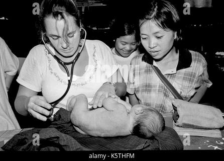 Dr. Mary Washburne untersucht ein Kind links im Wald an ist Geburt (mit Plazenta) an Shok La Flüchtlingslager im Nordwesten von Thailand; ein Lager nur für diejenigen mit Cholera Symptome zu sterben. September, 1996. Stockfoto