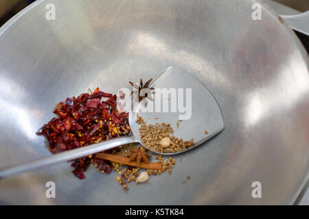 Popping Massaman Curry Kräuter Zutaten auf Stahl wok pfanne. Bild der traditionelle thailändische Küche aus frischen Zutaten während der kochkurs in Stockfoto