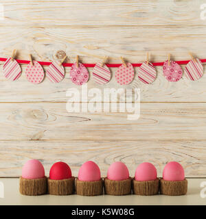 Ostereier und Ostern Dekor Papier Eiern mit einer rosa Schleife auf einem hölzernen Hintergrund. Selektiven Fokus. Stockfoto