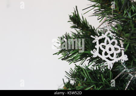 Handgefertigte Schneeflocke Schmuck am Weihnachtsbaum mit weißem Hintergrund. Nahaufnahme, flachen konzentrieren. Stockfoto