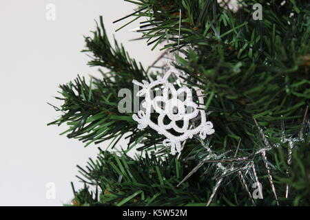 Handgefertigte Schneeflocke Schmuck am Weihnachtsbaum mit weißem Hintergrund. Nahaufnahme, flachen konzentrieren. Stockfoto