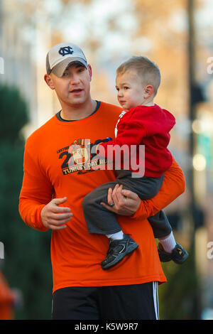 OISE, IDAHO - 22. NOVEMBER: Mann hält seinen Sohn während in der 5k Türkei Tag Rennen in Boise, Idaho konkurrieren am 22. November 2012 Stockfoto