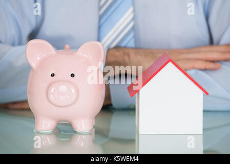 Close-up ein Geschäftsmann mit Piggyback und Modell Haus Stockfoto