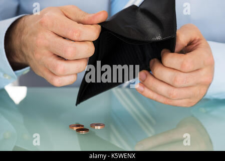 Geschäftsmann Kontrolle seine Brieftasche mit Münzen auf Schreibtisch Stockfoto