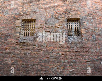 Zwei Fenster mit eisernen Gitter auf einer alten Mauer eines Gefängnisses in einer mittelalterlichen Burg Stockfoto