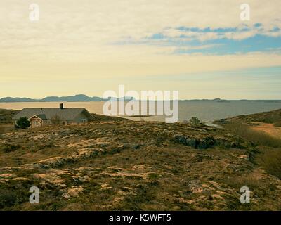 Moderne steinigen Familienhaus auf der Feder am Meer, Norwegen, Island. Ein traditionelles Steinhaus mit einem wunderschönen Blick auf das Meer. Felsige Landschaft mit Stockfoto
