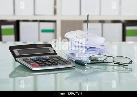 Empfänge in Papier Nagel mit Taschenrechner und Brillen auf Schreibtisch Stockfoto