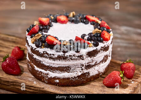 Ein Schnitt von Kuchen mit Sahne und Erdbeeren Früchte auf Holz Tisch Stockfoto