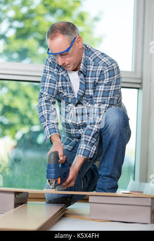 Senior Tischler Schneiden von Holz mit Bandsäge auf der Baustelle Stockfoto