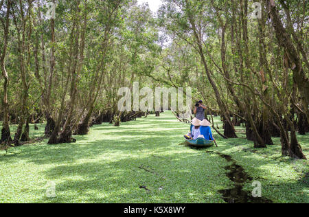 Der Fährmann bringt Reisende auf einer Bootstour entlang der Kanäle im Mangrovenwald. Es ist ein Eco Tourismus Bereich am Mekong Delta Stockfoto