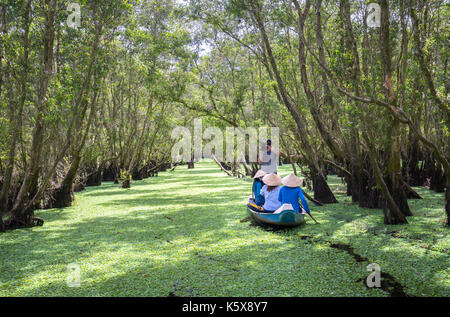 Der Fährmann bringt Reisende auf einer Bootstour entlang der Kanäle im Mangrovenwald. Es ist ein Eco Tourismus Bereich am Mekong Delta Stockfoto