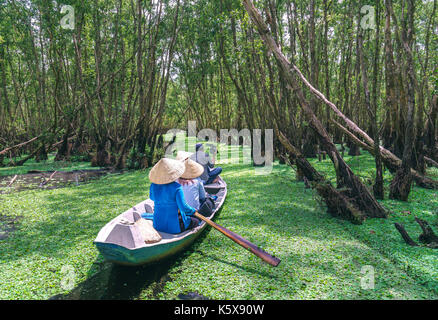 Der Fährmann bringt Reisende auf einer Bootstour entlang der Kanäle im Mangrovenwald. Es ist ein Eco Tourismus Bereich am Mekong Delta Stockfoto