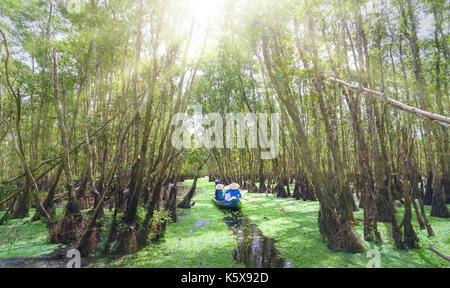Der Fährmann bringt Reisende auf einer Bootstour entlang der Kanäle im Mangrovenwald. Es ist ein Eco Tourismus Bereich am Mekong Delta Stockfoto