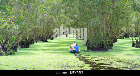 Der Fährmann bringt Reisende auf einer Bootstour entlang der Kanäle im Mangrovenwald. Es ist ein Eco Tourismus Bereich am Mekong Delta Stockfoto
