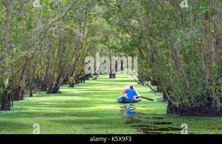 Der Fährmann bringt Reisende auf einer Bootstour entlang der Kanäle im Mangrovenwald. Es ist ein Eco Tourismus Bereich am Mekong Delta Stockfoto
