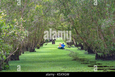 Der Fährmann bringt Reisende auf einer Bootstour entlang der Kanäle im Mangrovenwald. Es ist ein Eco Tourismus Bereich am Mekong Delta Stockfoto
