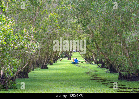 Der Fährmann bringt Reisende auf einer Bootstour entlang der Kanäle im Mangrovenwald. Es ist ein Eco Tourismus Bereich am Mekong Delta Stockfoto
