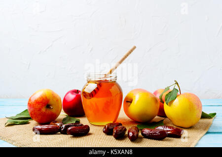 Honigtopf, Termine und frische Äpfel mit grünen Blättern auf der Leinwand Serviette. Rosch Haschanah Konzept. Jewesh neues Jahr Symbole. Stockfoto