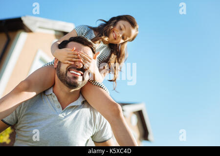 Kleines Mädchen für Väter Augen beim Sitzen auf den Schultern Stockfoto