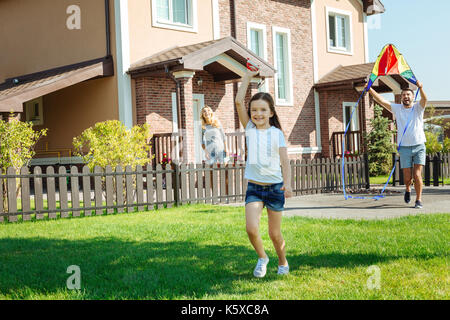 Adorable girl Flying a Kite mit ihrem Vater in Hof Stockfoto