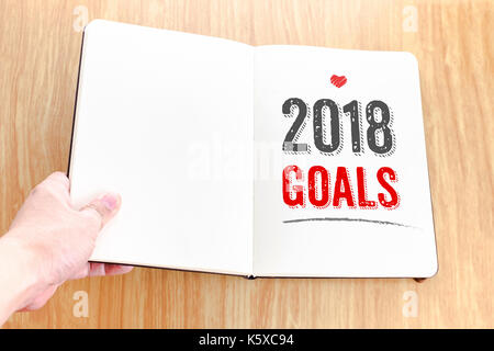 Hand öffnen Notebook mit 2018 Ziele es auf hölzernen Tisch legen, Entschließungen des Lebens. Stockfoto