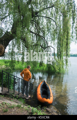 Mann in orange Jacke in der Nähe von Orange Kajak Stockfoto