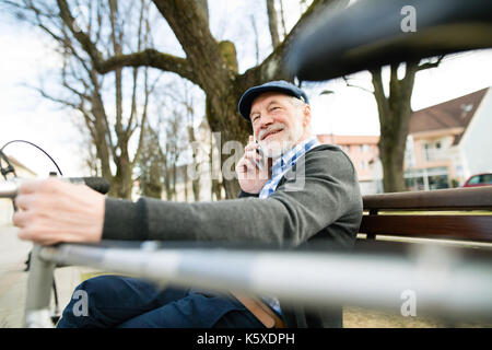 Senior Mann mit Fahrrad und Smartphone-Anruf tätigen Stockfoto