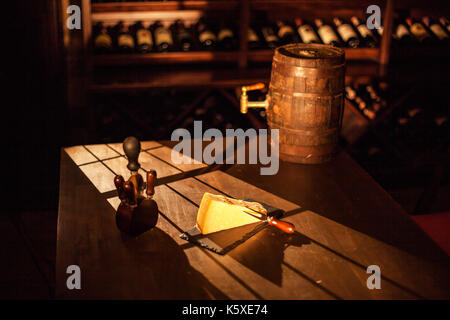 Zusammensetzung wenn Stück Käse und Zubehör neben Holz- Wein Faß auf einem Holztisch in einem Weinkeller. Stockfoto