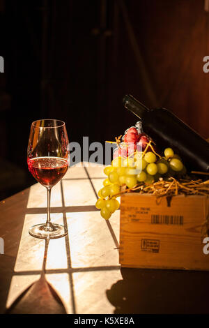 Wein Glas neben dem Obst und Wein aus der Flasche. Zusammensetzung auf dem Holztisch und Sonnenlicht. Stockfoto