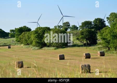 Windkraftanlagen am Hügel über runde Heuballen in einem Oklahoma Feld. Stockfoto