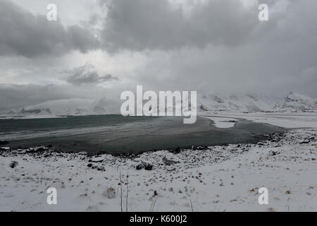 E-SEwards Blick auf verschneite Ytresand Strand - Sandbotnen Bucht - stürmischen Himmel. - Volandstinden-Sautinden Flakstadtinden Nonstinden-Stortinden-Mounts. Ytresand Stockfoto