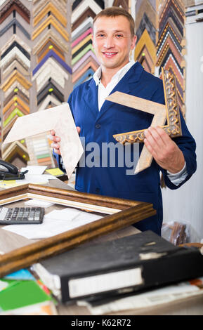Portrait von glücklichen Verkäufer arbeiten mit Bilderrahmen im Atelier Stockfoto
