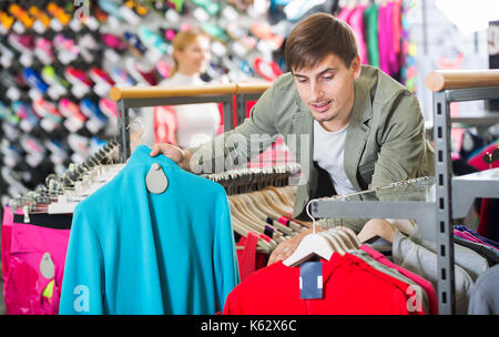 Lächelnd mann Auswahl eine warme Jacke im Sport Abteilung Stockfoto