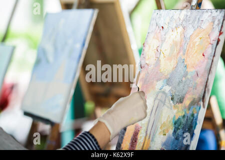 Artist's Hand mit Spachtel und Leinwand Stockfoto
