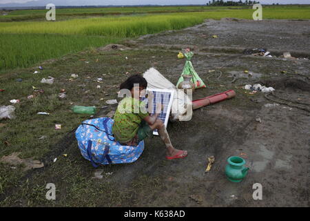 Teknaf, Bangladesch. September 2017. Ein Rohingya-Mädchen rast auf einem Feld nach dem Überqueren der Grenze zwischen Bangladesch und Myanmar in Teknaf. Rohingya Flüchtling geht schlammigen Weg nach der Überquerung der Bangladesch-Myanmar Grenze, in Teknaf. Quelle: Md. Mehedi Hasan/Pacific Press/Alamy Live News Stockfoto