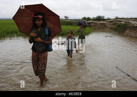 Teknaf, Bangladesch. September 2017. Rohingya-Kinder gehen nach dem Überqueren der Grenze zwischen Bangladesch und Myanmar in Teknaf durch das Wasser. Rohingya Flüchtling geht schlammigen Weg nach der Überquerung der Bangladesch-Myanmar Grenze, in Teknaf. Quelle: Md. Mehedi Hasan/Pacific Press/Alamy Live News Stockfoto